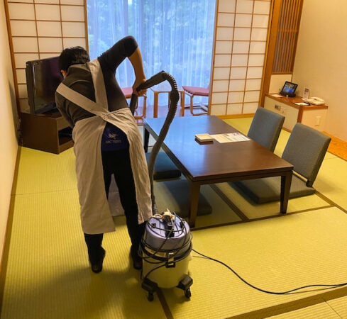 和室に掃除機をかけている客室清掃スタッフ